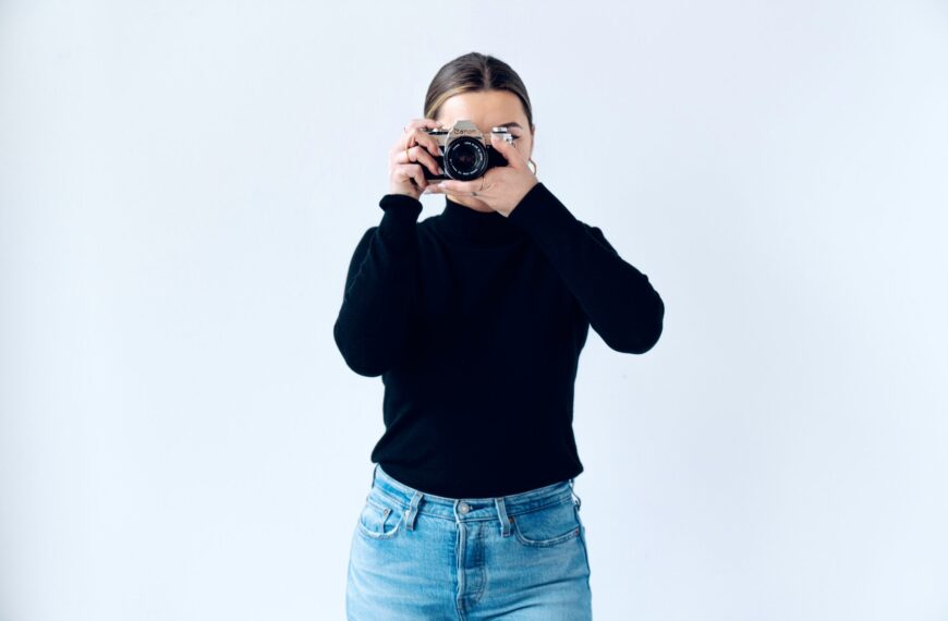 woman in black long sleeve shirt and blue denim jeans holding black and silver camera