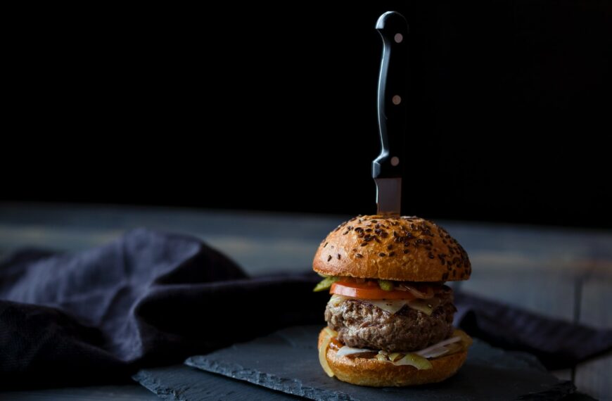 burger skewered with knife near black textile