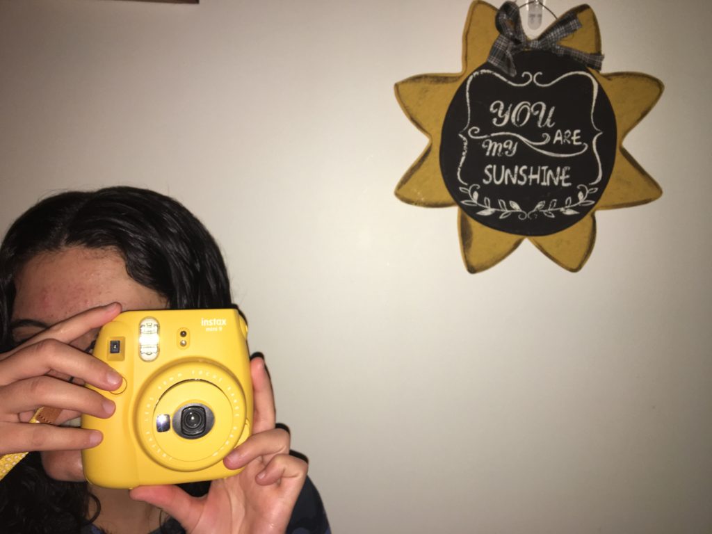 girl taking photo with yellow camera to capture final year of college
