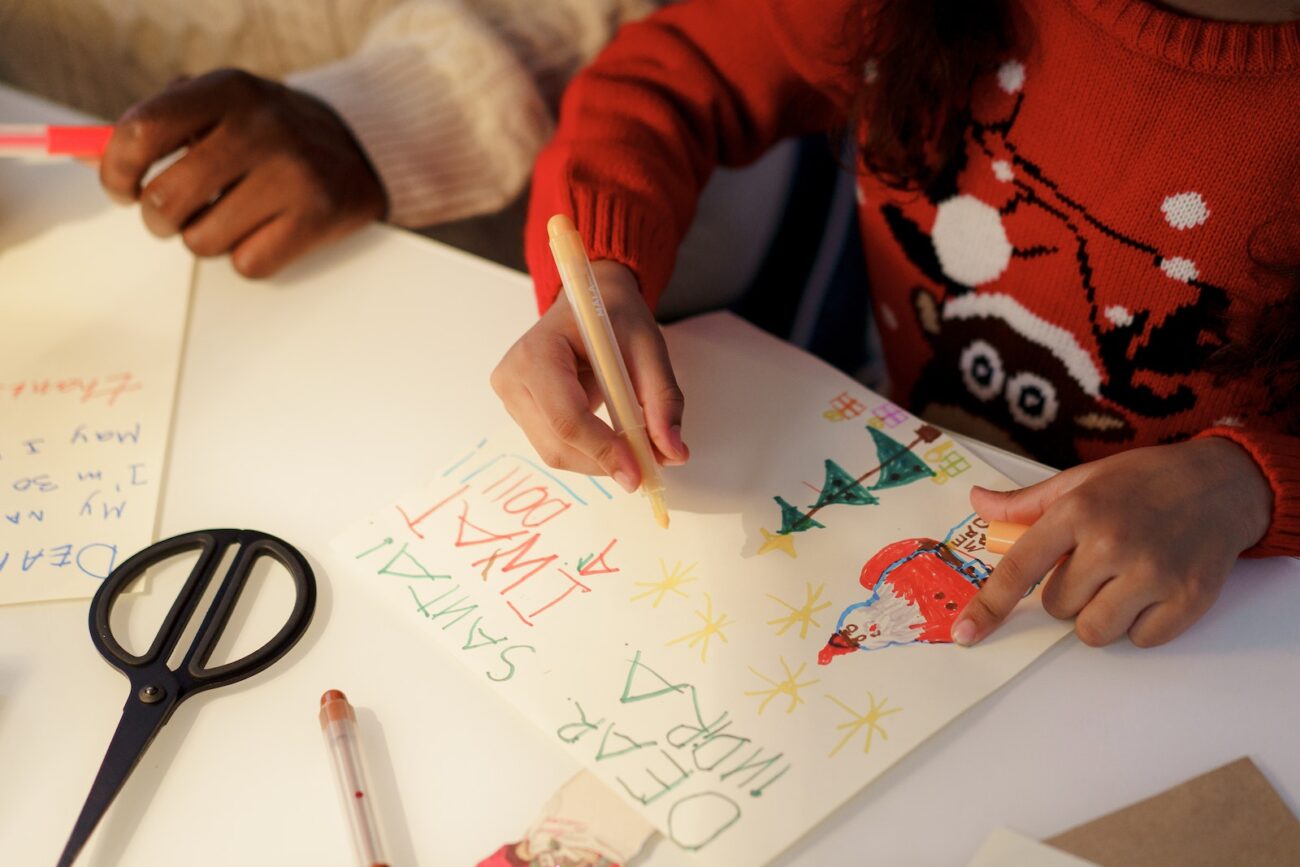 A Person in Red Sweater Making a Christmas Letter